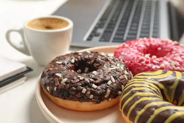 Bad eating habits at workplace. Sweet glazed donuts on white table, closeup