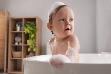 Evde köpüklü banyo yapan şirin bir bebek.