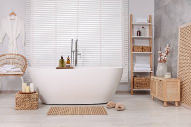 Bambu banyo paspası ve beyaz küveti olan şık bir banyo.