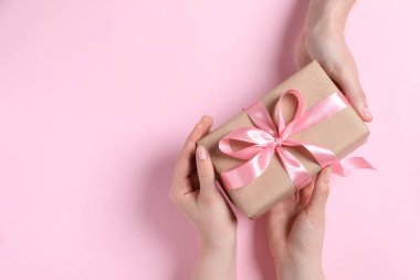 Erkek, pembe arka plandaki kadına hediye paketi veriyor. Metin için boşluk