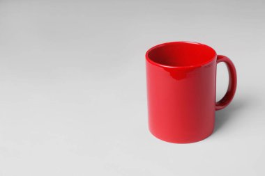 Açık gri arkaplanda kırmızı seramik bardak. Metin için boşluk