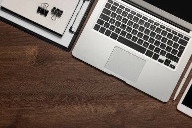 Diz üstü bilgisayar ve ahşap masadaki farklı kırtasiye malzemeleri, metin için yeri olan düz bir yer. Merkez Ofis