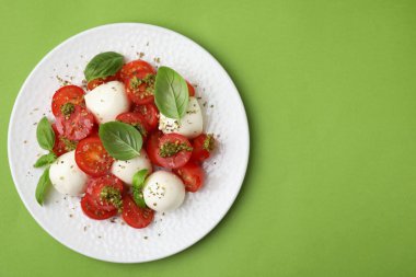 Domatesli Caprese salatası, mozzarella topları ve yeşil arka planda fesleğen. Metin için boşluk