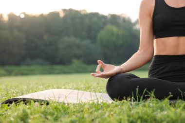 Dışarıdaki yoga minderinde Padmasana antrenmanı yapan bir kadın, yakın çekim ve mesaj için yer. Lotus pozu