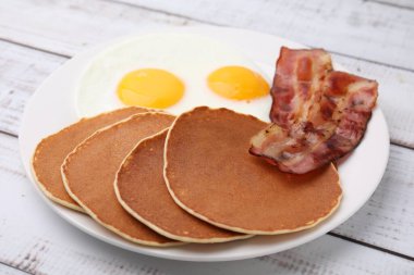 Beyaz ahşap masada omlet ve pastırmalı leziz krepler, yakın plan.