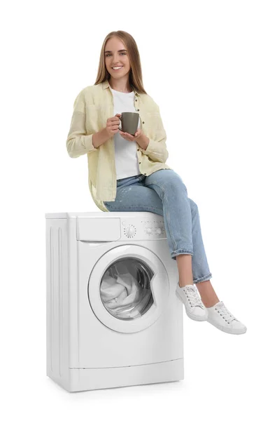 白い背景に対する洗濯機の洗濯機の飲み物のコップの美しい若い女性 — ストック写真