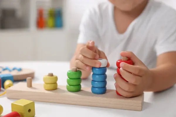 Motor skills development. Little boy playing with stacking and counting game at table indoors, closeup