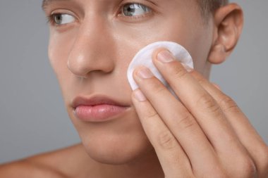 Gri arkaplanda pamuk yastıklı yakışıklı adam, yakın plan.