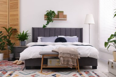 Çift kişilik yatağı ve güzel yeşil çiçekleri olan şık bir yatak odası. Modern iç mimari
