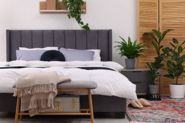 Çift kişilik yatağı ve güzel yeşil çiçekleri olan şık bir yatak odası. Modern iç mimari