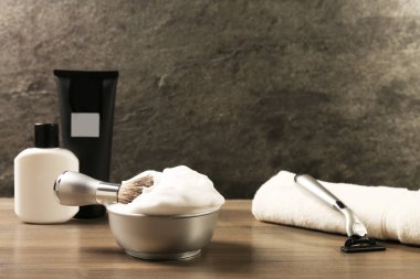 Erkeklerin tıraş aletleri ve köpük seti ahşap masada.