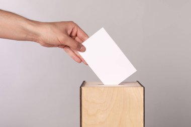 Adam oyunu açık gri arka planda sandığa koyuyor, yakın plan.