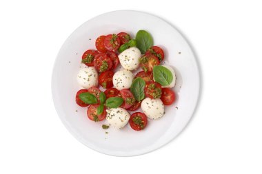 Bir tabak lezzetli salata, domatesli Caprese, mozzarella topları ve beyaz üzerine izole edilmiş fesleğen.