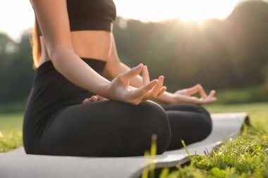 Dışarıdaki yoga minderinde Padmasana egzersizi yapan kadın, yakın plan. Lotus pozu