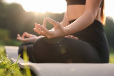 Dışarıdaki yoga minderinde Padmasana egzersizi yapan bir kadın, yakın çekim ve alçak açı. Lotus pozu