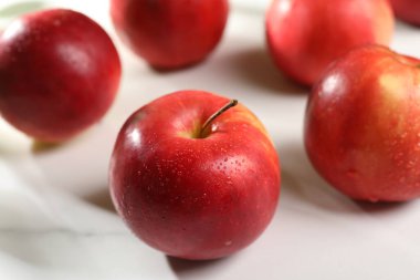 Taze kırmızı elmalar beyaz masaya damlıyor, yakın plan.