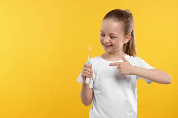 Щаслива Дівчина Тримає Електричну Зубну Щітку Жовтому Тлі Простір Тексту — стокове фото