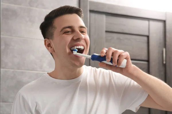 バスルームで電気歯ブラシで歯を磨く男 — ストック写真