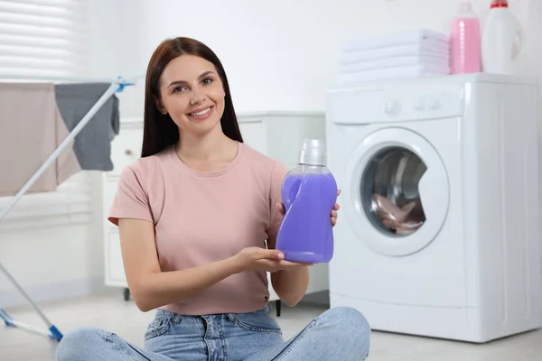 Woman holding fabric softener in bathroom, space for text