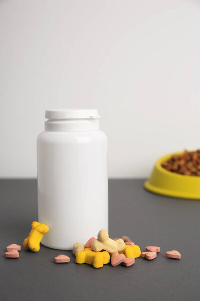 Bottle with pet vitamins on grey table, closeup