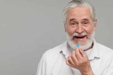 Kıdemli adam gri arka planda hap alıyor. Metin için boşluk