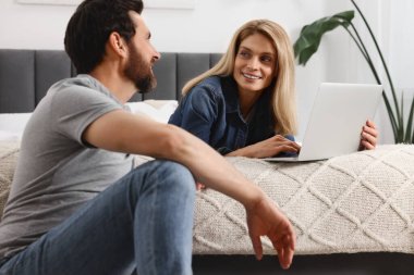 Mutlu çift birlikte vakit geçirip evde dizüstü bilgisayar kullanıyor.