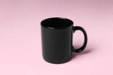 Pembe arka planda siyah bir seramik bardak.