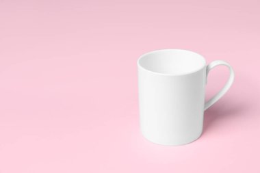 Pembe arka planda bir beyaz seramik bardak, metin için boşluk