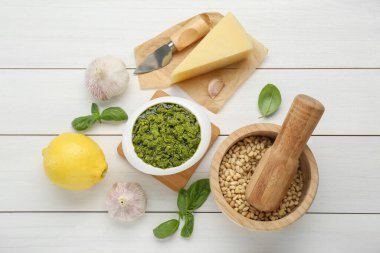 Lezzetli pesto sosu kasede ve malzemeler beyaz ahşap masada, düz yerde.