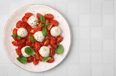 Domatesli Caprese salatası, mozzarella topları ve beyaz fayanslı fesleğen, üst manzara. Metin için boşluk