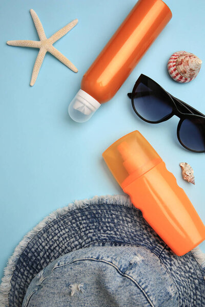 Flat lay composition with bottles of sunscreen on light blue background