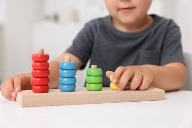 Motor beceri geliştirme. Küçük çocuk masa içinde istifleme ve sayma oyunu oynuyor, yakın plan.