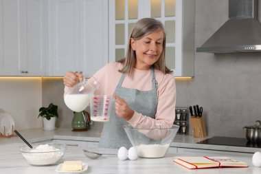 Mutfakta yemek tarifi kitabıyla kıdemli kadın.