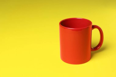 Sarı arkaplanda bir kırmızı seramik bardak, metin için boşluk