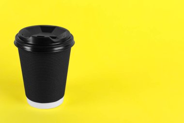 Sarı arka planda plastik kapaklı siyah kağıt bardak, metin için boşluk. Kahve hazır.