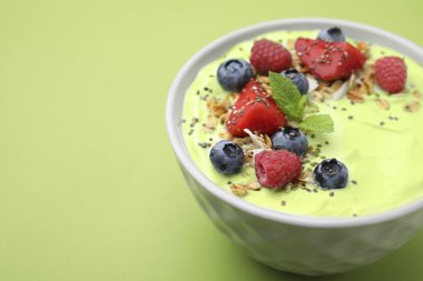 Lezzetli kirazlı smoothie kasesi yeşil arka planda böğürtlen ve yulaf ezmesi ile servis edilir, yazı için yeri olan yakın plan. Sağlıklı kahvaltı.