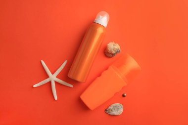 Güneş kremi şişeleri, deniz kabukları ve mercan zemin üzerinde deniz yıldızları, düz yatıyordu.