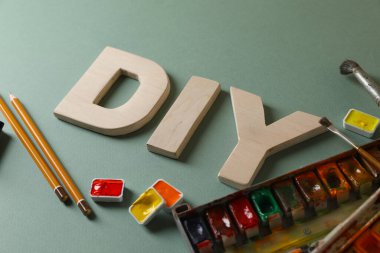 Kısaltma DIY harflerden ve soluk yeşil arka planda farklı boya malzemelerinden yapılmış, yakın plan