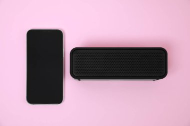 Portatif bluetooth hoparlör ve pembe arka planda akıllı telefon, düz konum. Ses ekipmanları