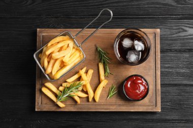 Lezzetli patates kızartması, ketçap ve soda. Koyu ahşap masa, üst manzara.