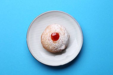 Turkuaz arka planda pudra şekerli jöleli Hanuka çöreği.