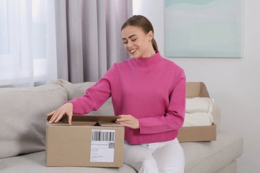Evde paketleri açan mutlu kadın. Çevrimiçi mağaza