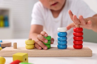 Motor beceri geliştirme. Küçük çocuk masa içinde istifleme ve sayma oyunu oynuyor, yakın plan.