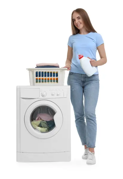 白い背景の洗濯機の近くの洗剤および洗濯のバスケットが付いている美しい若い女性 — ストック写真
