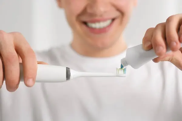 Человек Сжимает Зубную Пасту Тюбика Электрическую Зубную Щетку Размытом Фоне — стоковое фото