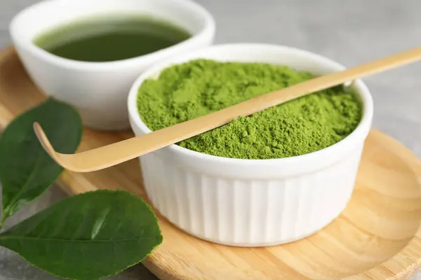 Green matcha powder and bamboo scoop on table, closeup