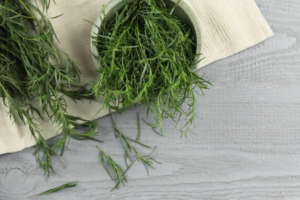 Fresh tarragon leaves on grey wooden table, flat lay. Space for text