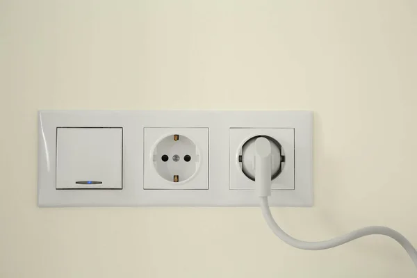 室内白色墙上插插头和电灯开关的电源插座 — 图库照片