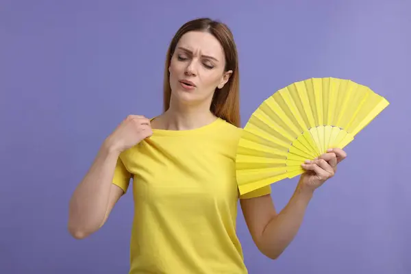 Schöne Frau Schwenkt Gelben Handfächer Sich Auf Violettem Hintergrund Abzukühlen — Stockfoto