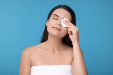 Açık mavi arka planda pamuk yastıklı genç bir kadın.